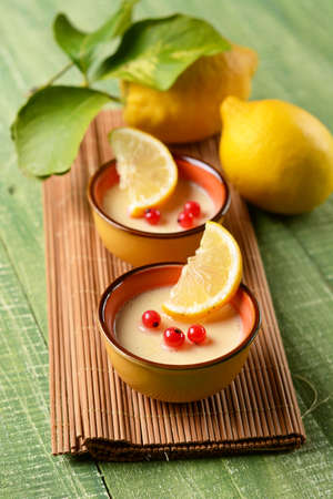 lemon dessert decorated with red currants in clay bowlの写真素材