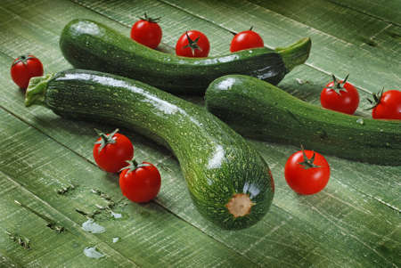 zucchini and cherry tomatoes on the green tableの写真素材
