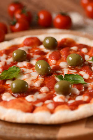 Italian pizza with green olives on cutting boardの写真素材