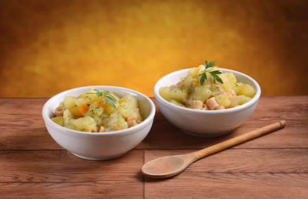 pasta with potatoes and carrots in two white bowlsの写真素材