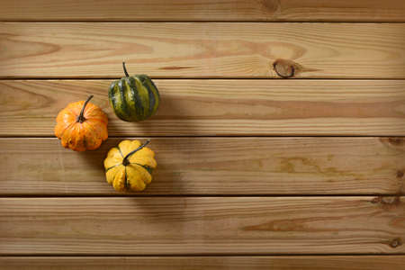 three small pumpkins on the wooden tableの写真素材