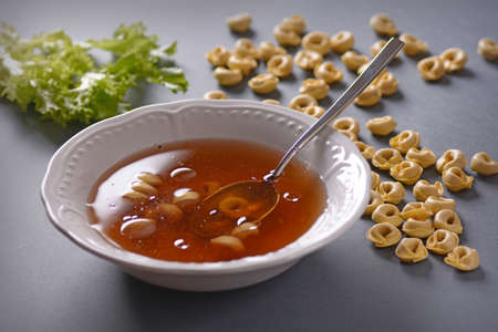 tortellini in broth in white plateの写真素材