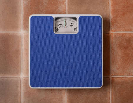 Bathroom scale isolated on terracotta floor background - closeupの写真素材