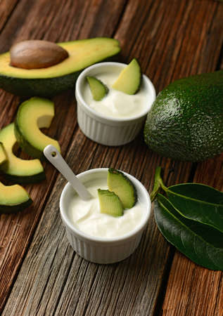 yogurt with avocado in bowl on wooden table - closeup