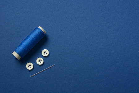 blue cotton thread, sewing buttons and tailor needle - blue background - closeupの写真素材