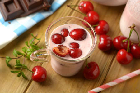 fresh yogurt with red cherries in the glass cup - closeupの写真素材