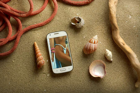 smartphone with photo sexy girl in swimsuit on the beach - closeupの写真素材