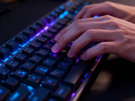 Close-up of female hands typing on the keyboard with blue lightの素材