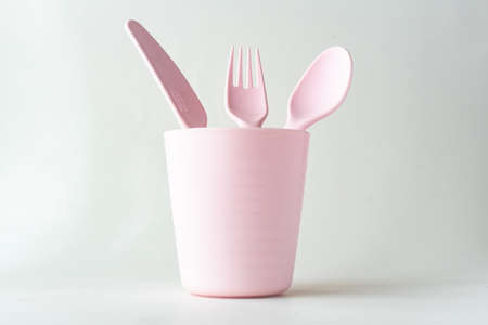 Plastic cup, spoon, fork and a knife isolated on white background