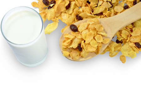 Cornflakes with currant isolated in a wooden spoon and a glass of milk on white background