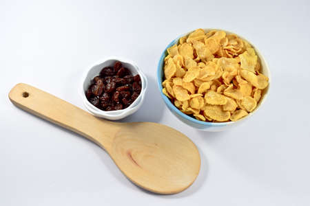 Cornflakes and currant in a wooden spoon on white backgroundの写真素材