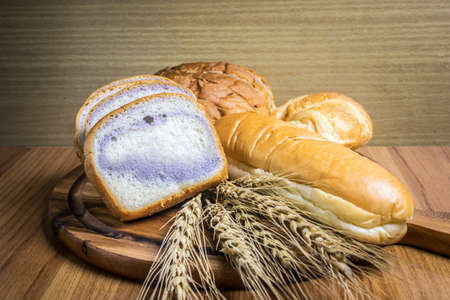 Bread on wooden background and wheat