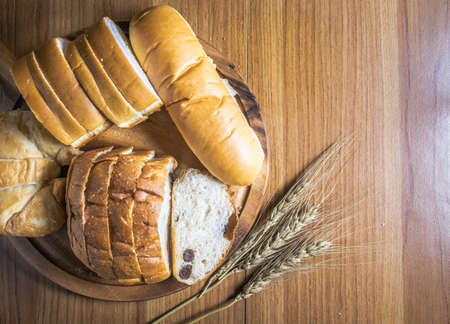Bread on wooden background with wheat and top viewの写真素材