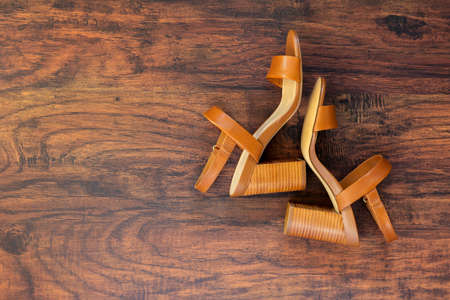 Elegant women shoes. Pair of brown leather summer women's high-heeled sandals on wooden floor. Top viewの写真素材