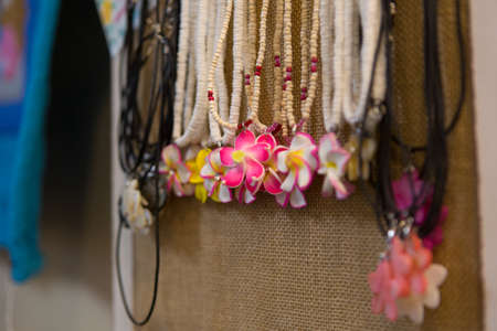 Beautiful coco beads necklaces with Plumeria Flower Pendants are for sale in a street market flower stand in Maui, Hawaii, USA.の写真素材