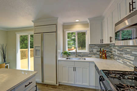 Beautiful open plan second floor white kitchen with traditional style kitchen cabinetry, mosaic...