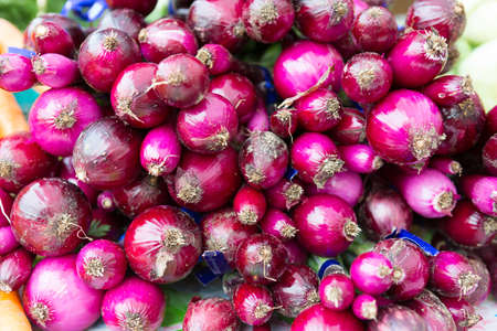 Close up of glossy rich burgundy onions at the farmers market.の写真素材