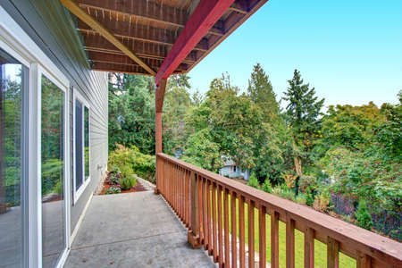 Luxury new construction home exterior. Back covered porch with concrete floor, wood handrails and...