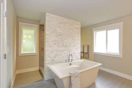 Amazing master bathroom accented with stone wall walk-through shower and freestanding bathtub over...