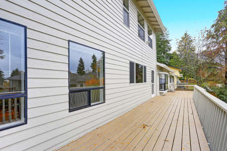 Lovely home features a wraparound deck lined with a wooden handrails overlooking the backyard.
