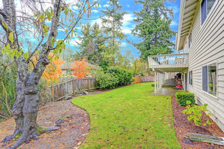Lovely home features a wraparound deck lined with a wooden handrails overlooking the backyard.
