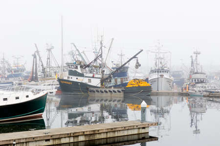SEATTLE, WA - OCTOBER 28, 2017: Fishing Boats reflected on the Puget Sound waters and Docked at Fishermen's Terminal in Seattle on a foggy morning.のeditorial素材