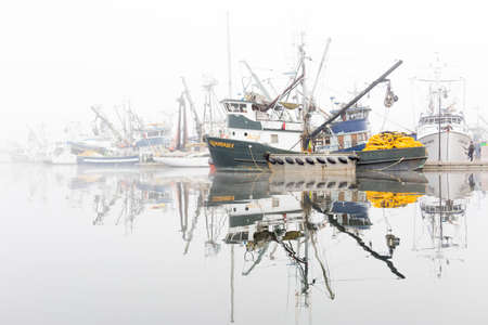 SEATTLE, WA - OCTOBER 28, 2017: Fishing Boats reflected on the Puget Sound waters and Docked at Fishermen's Terminal in Seattle on a foggy morning.のeditorial素材
