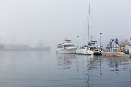 SEATTLE, WA - OCTOBER 28, 2017: Fishing Boats reflected on the Puget Sound waters and Docked at Fishermen's Terminal in Seattle on a foggy morning.のeditorial素材