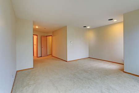 Empty apartment interior features white walls and beige carpet floor.