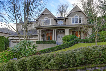Gorgeous big Craftsman home with gray wood exterior and cozy covered porch with columns. 