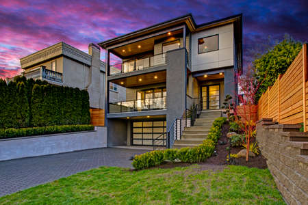 Luxury modern home exterior at sunset boasts four car garage with wide driveway. の写真素材