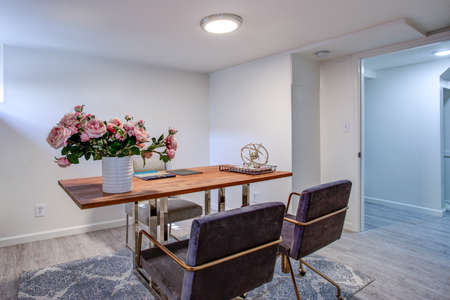 White home office with chrome and wood desk, two velvet chairs.
