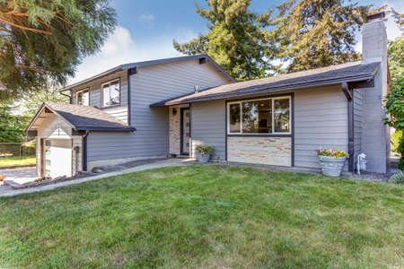Nice front view of a large blue house surrounded by tall trees.の写真素材