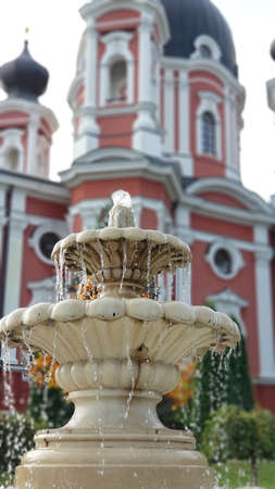 The operating water fountain against the background of the monastery in Moldova.