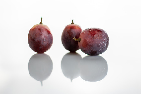 Three red grapes wet isolated on white backgroundの写真素材