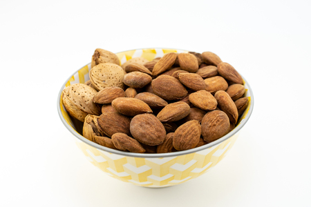 Group of almonds in a bowl on white backgroundの写真素材