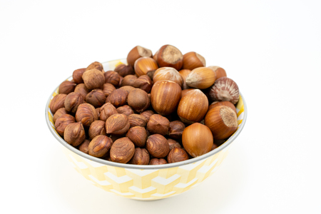 Group of hazelnuts in a bowl isolated on white backgroundの写真素材