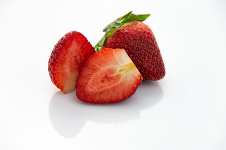 Sliced red strawberries with green leaves isolatedの写真素材