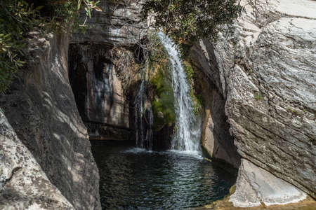 Nature with a river of mineral water with a waterfall and surrounded by gray rocks and green vegetation and plantsの写真素材