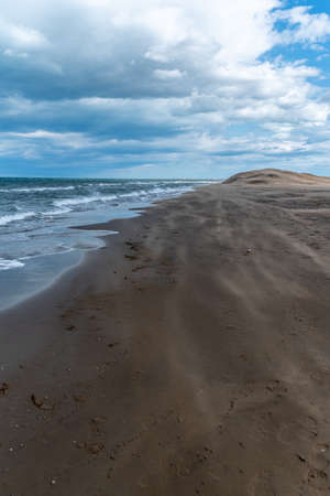 Beach with waves of the sea and the shore of sand. Brown, blue and gray colorsの写真素材