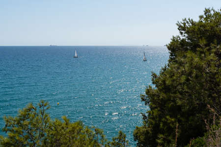 View of the beautiful blue Mediterranean sea with rocks near the shore with waves on a sunny day...