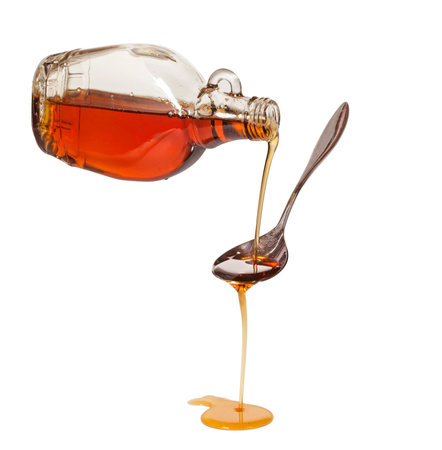 Bottled maple syrup dripping on teaspoonの写真素材