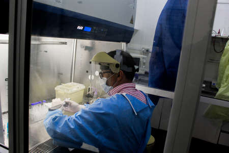 Biochemist sitting processing covid19 samples with all protective measuresの写真素材