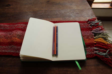 open book with blank leaves next to colored pencils