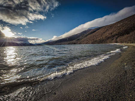 Sunset over the lake on a pebble beach with clear skyの写真素材