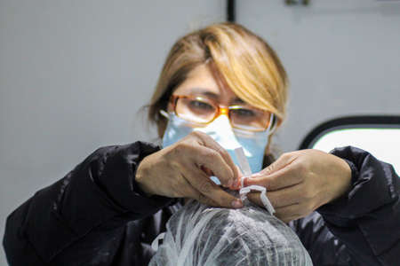 Nurse with her face mask on helping to dress the doctorの写真素材