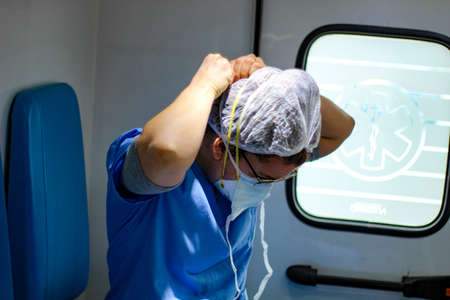 Female doctor putting on the double face mask while riding in the ambulanceの写真素材