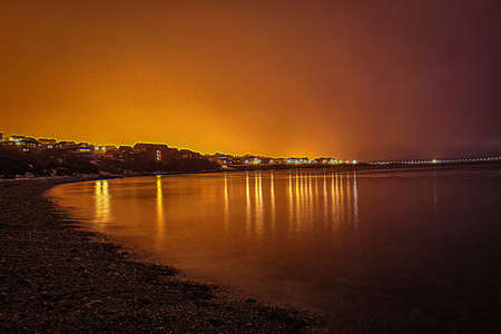 Dusk over the lake shore with the village lights in the backgroundの写真素材