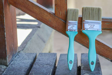 Two paintbrushes standing on a ladder drying in the air