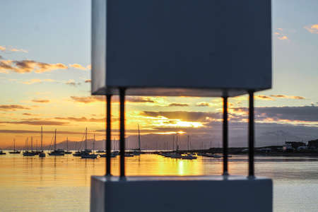 sunset over the lake shore with sailboats in the background